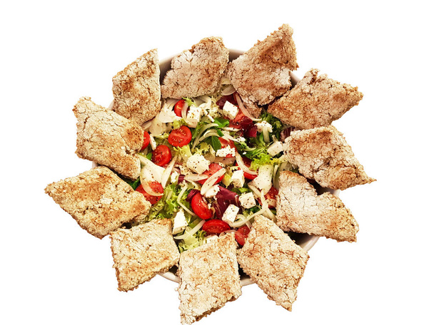 Mediterrane groente salade met soepele segmenten van zelfgebakken brood, verspreid rond de rand van de plaat. Veggirarian schotel op een afgelegen witte achtergrond. Traditionele keuken voor weight loss. - Foto, afbeelding