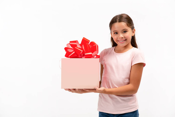 Retrato de niña feliz con caja de regalo sobre fondo blanco. Copiar espacio en la caja
 - Foto, Imagen