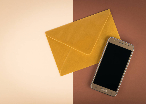 Gold smartphone with envelope on two color background - Photo, Image