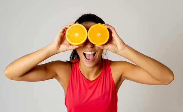 Laughing funny charming joyful attractive fashion model woman holding orange slice near her eyes in beauty treatment Great food for a healthy lifestyle concept isolated on grey background. - Photo, image