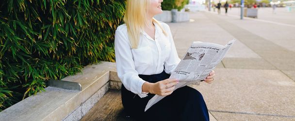 屋外の顔間近で新聞を読んでいる女性. - 写真・画像