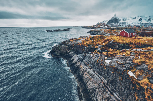 Clif with traditional red rorbu house on Lofoten Islands, Norway - 写真・画像