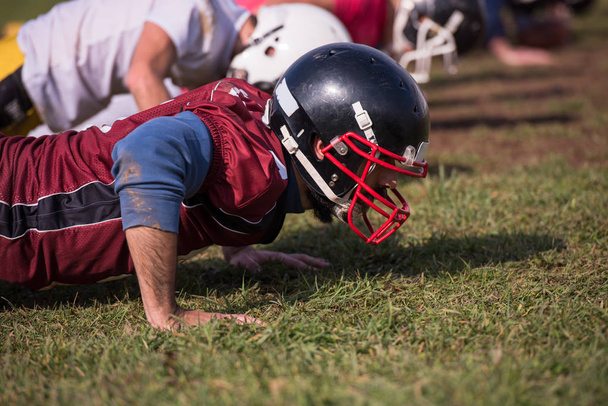 american football team doing push ups during training at the field - 写真・画像