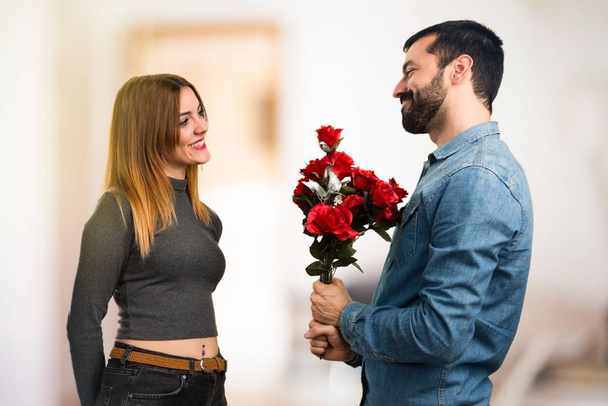 Man and woman holding flowers on unfocused background - Photo, Image