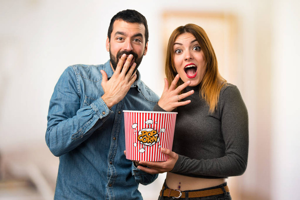 Άνδρας και γυναίκα τρώει popcorns σε αόριστες φόντο - Φωτογραφία, εικόνα