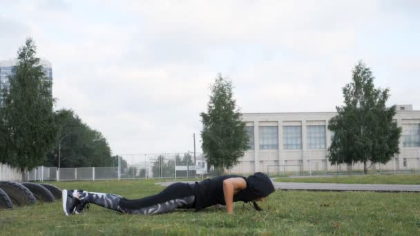 Push up nebo tisk zvýší výkon mladá žena. Dívka cvičit na trávě crossfit silového tréninku na stadionu - Záběry, video