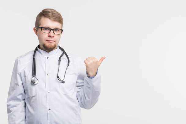 Médico masculino apontando o dedo para o espaço de cópia, isolado em fundo branco. Conceito médico
. - Foto, Imagem
