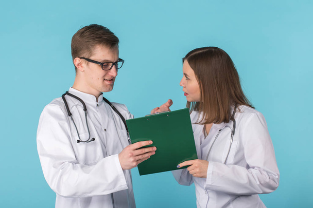 Young male and female doctors discussing in blue background - Valokuva, kuva