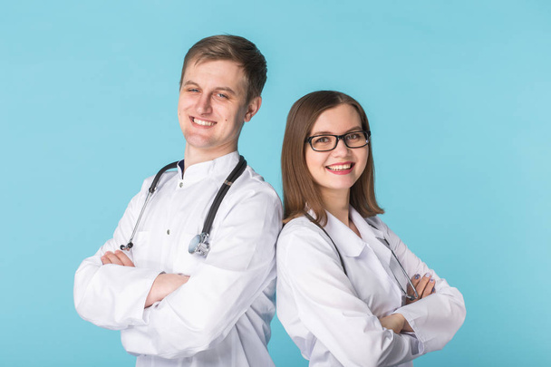 Mannelijke en vrouwelijke artsen in witte jassen op blauwe achtergrond - Foto, afbeelding