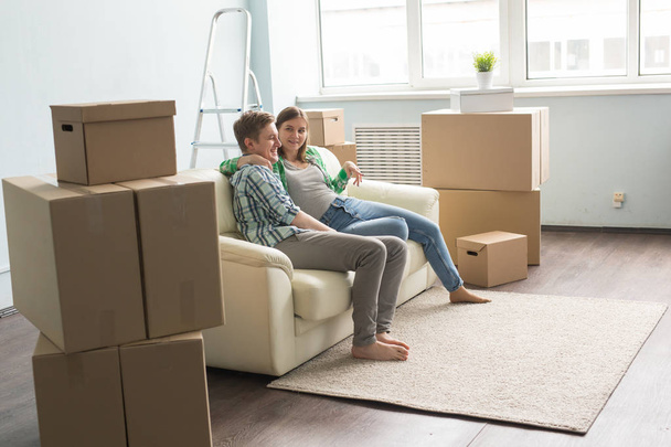 Νέο σπίτι, κινείται και real estate - νεαρό ζευγάρι κάθεται στον καναπέ και μιλά μαζί - Φωτογραφία, εικόνα