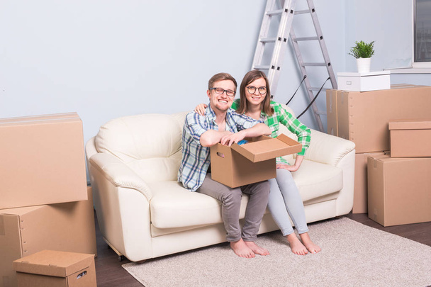 移転、マンション、不動産、移動の概念 - 若いカップルのソファーに座っている人し、ボックスを開きます - 写真・画像
