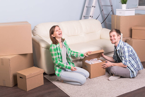 Umzugs- und Immobilienkonzept - glückliches Paar hat Spaß beim Auspacken von Kartons im neuen Zuhause - Foto, Bild