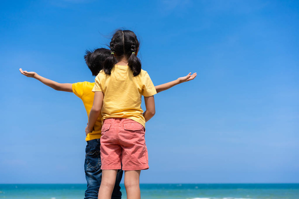 Χαλαρωτικό ασιατικό παιδιά στην παραλία με μπλε ουρανό και θάλασσα φόντο - Φωτογραφία, εικόνα