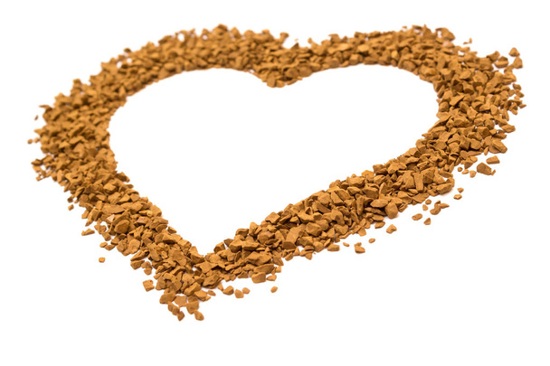 Dry instant coffee granules in the shape of a heart - brown texture, on a white background - Photo, Image