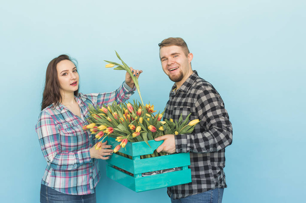 Joyeux fleuristes fixer des tulipes dans une grande boîte en bois sur fond bleu
 - Photo, image