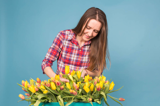 Květinářství veselá mladá žena s box tulipány modré pozadí - Fotografie, Obrázek