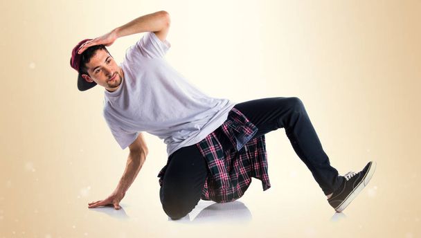 Man Streetdance dansen op okergeel achtergrond - Foto, afbeelding