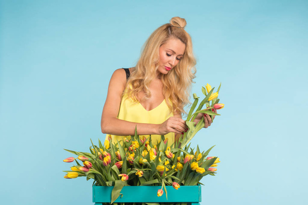 Blondynka, młoda kobieta z bukietem tulipanów na niebieskim tle - Zdjęcie, obraz