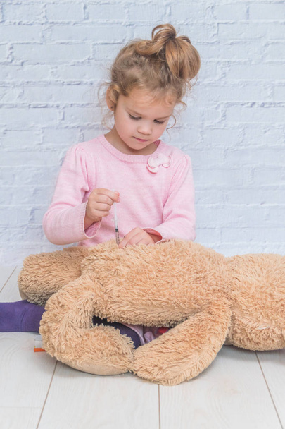 child, a girl makes a shot to the toy bear, the insulin syringe - Zdjęcie, obraz