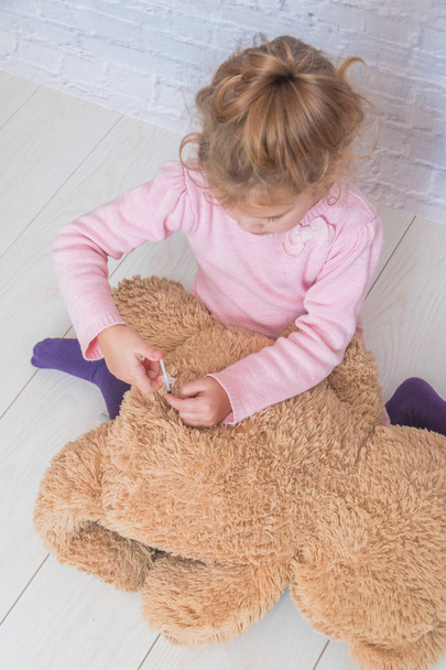 child, a girl makes a shot to the toy bear, the insulin syringe - Zdjęcie, obraz