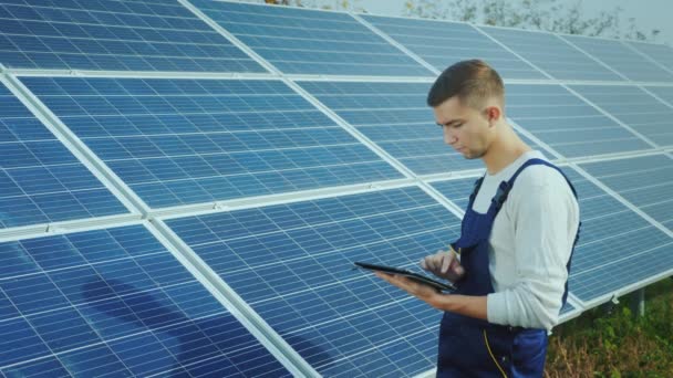 The engineer uses the tablet on the background of solar panels. Alternative energy and solar energy - Felvétel, videó