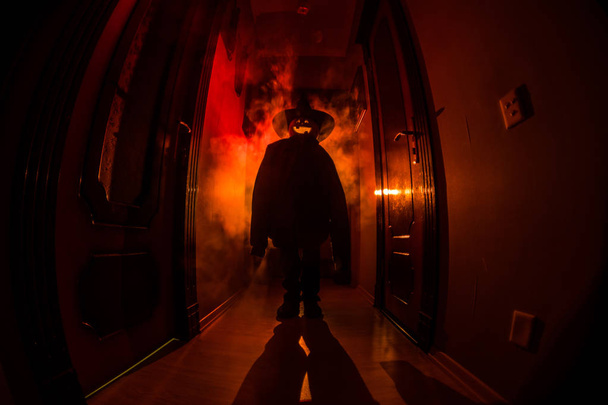 Concept d'Halloween. Silhouette effrayante dans le couloir sombre avec tête de citrouille. Lumière tonique avec brouillard sur le fond
. - Photo, image