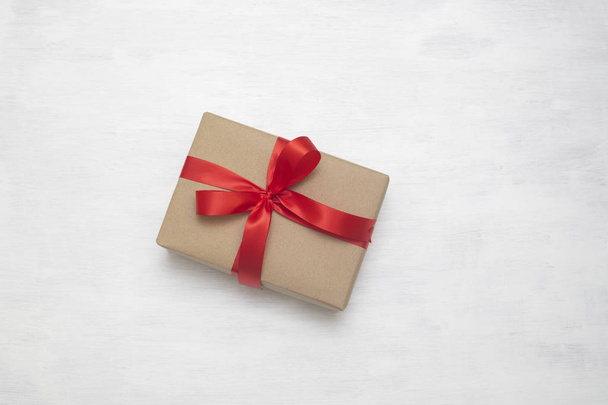 Wrapped vintage brown gift box with red ribbon bow, isolated on white, to send the good feeling to special one - Photo, Image