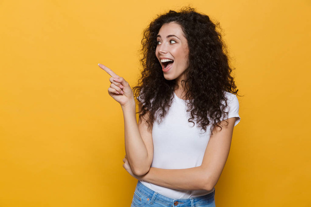 Photo of beautiful excited young cute woman posing isolated over yellow background pointing. - Fotó, kép