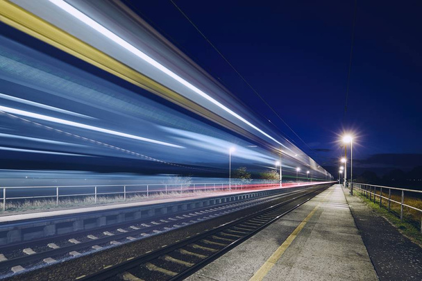 Light trails of passenger train commuting to railroad station at night. - Foto, immagini