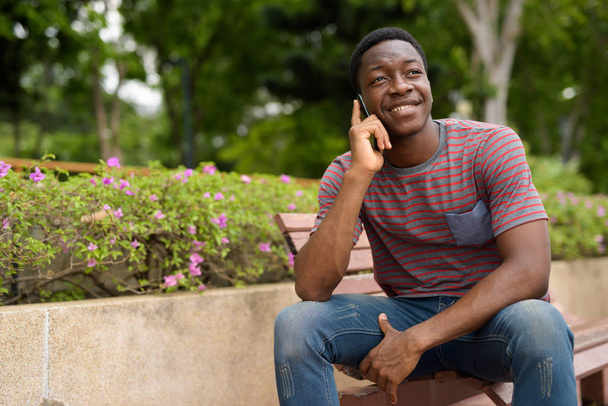 Homem africano feliz falando no telefone no parque
 - Foto, Imagem