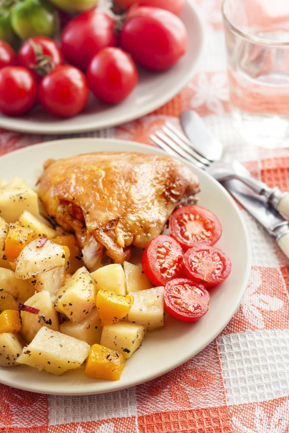 Baked chicken thigh with baked potatoes and pumpkin garnish on a plate - Photo, Image