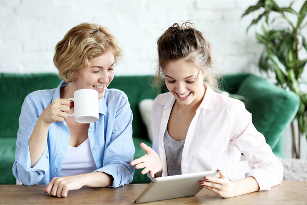 lifestyle, tehnology and people concept: mother and adult daughter using tablet computer at home - Foto, afbeelding