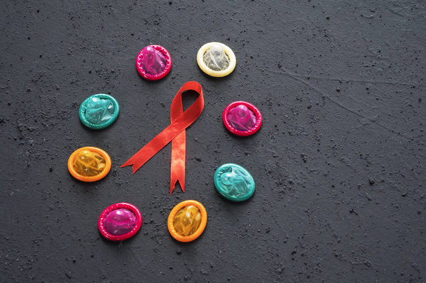 Image of colorful condoms shaped a circle with red ribbon on the table  - Foto, imagen