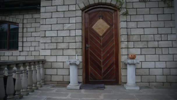 Porta da frente para uma casa decorada com abóbora Halloween. Abóbora de Halloween em uma porta íngreme à noite
 - Filmagem, Vídeo