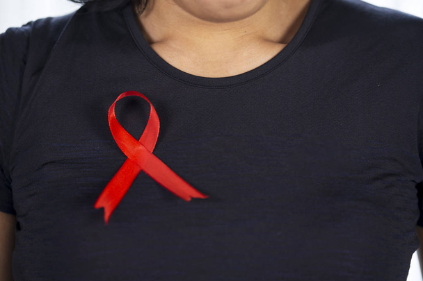 Close up of unknown woman wearing black clothes with red ribbon. World AIDS day concept   - Photo, Image