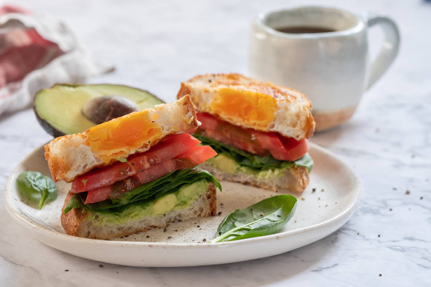 Egg in a hole sandwich with avocado, spinach and tomato - 写真・画像