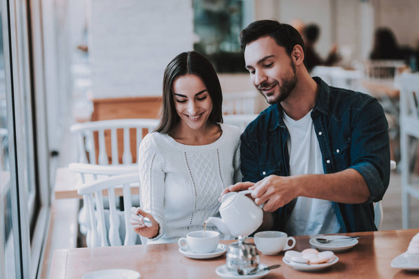 Tea. Cheerful Girl.Teapot. Bonding. Cupcake. Leisure Time.Together in Cafe. Happy Together. Smiling People. Love Story. Tea Party.Have Fun. Enjoyment. Guy and Girl. Good Relationship. Happy Holidays. - Foto, afbeelding