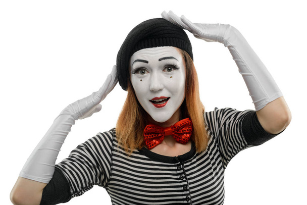 Woman tries on new hat. A pantomime sketch, performed by a female mime artist, touching head with hands and looking at the imaginary mirror. - Photo, image