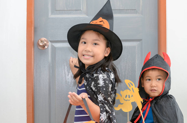 cute girl wear witches are knocking on the door with little boy devil, Halloween concept - Photo, Image