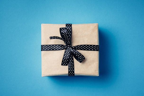 Verpakt geschenkdoos met lint strik op een blauwe achtergrond - Foto, afbeelding