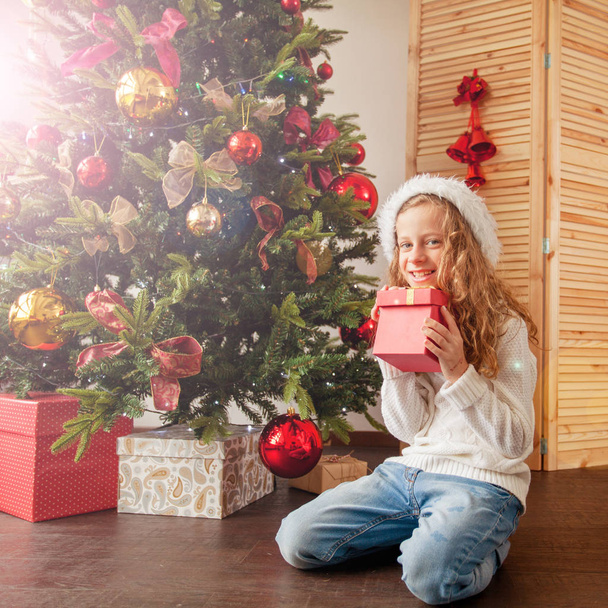 Child with gift near christmas tree - 写真・画像
