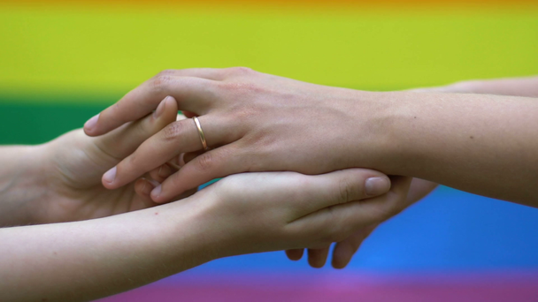 Para lesbijek sobie pierścienie na rainbow flaga tło, lgbt, miłość tej samej płci - Materiał filmowy, wideo