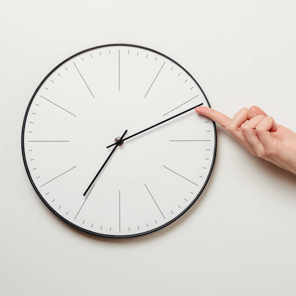 Czas zatrzymania ręka kobiety na okrągły zegar, kobiece trwa minutę strzałkę zegara powrotem, zarządzanie czasem oraz koncepcji terminu - Zdjęcie, obraz