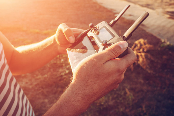 Homem segurando controlador remoto para voar em drone ou quadricóptero em mãos
 - Foto, Imagem