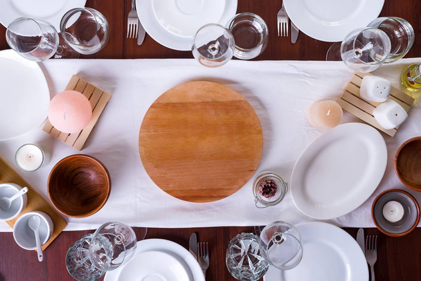 Посуда и украшения для сервировки праздничного стола. Тарелки, бокалы и столовые приборы с декоративным текстилем на деревянном фоне. Копирование пространства
 - Фото, изображение