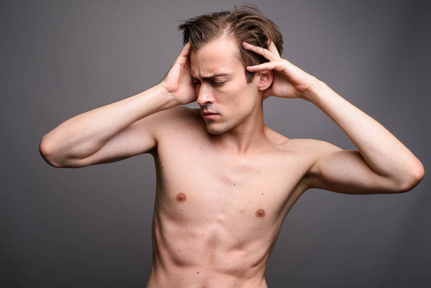 Young handsome man shirtless against gray background - Zdjęcie, obraz