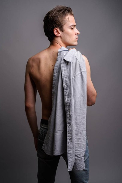 Молодий красивий чоловік без сорочки на сірому фоні
 - Фото, зображення