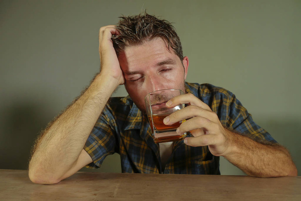 young attractive wasted and depressed addict and alcoholic man with whiskey glass thoughtful and sad failing resisting temptation to drink falling into alcohol abuse addiction and alcoholism problem  - Фото, зображення