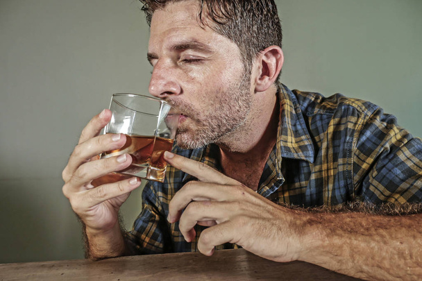 young attractive wasted and depressed addict and alcoholic man with whiskey glass thoughtful and sad failing resisting temptation to drink falling into alcohol abuse addiction and alcoholism problem  - Fotografie, Obrázek