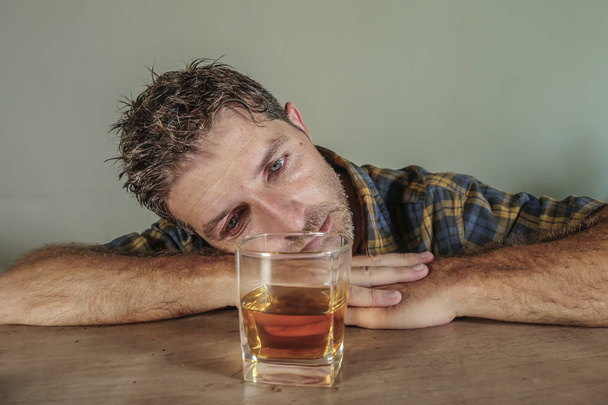 young attractive wasted and depressed addict and alcoholic man with whiskey glass thoughtful and sad failing resisting temptation to drink falling into alcohol abuse addiction and alcoholism problem  - Foto, Bild